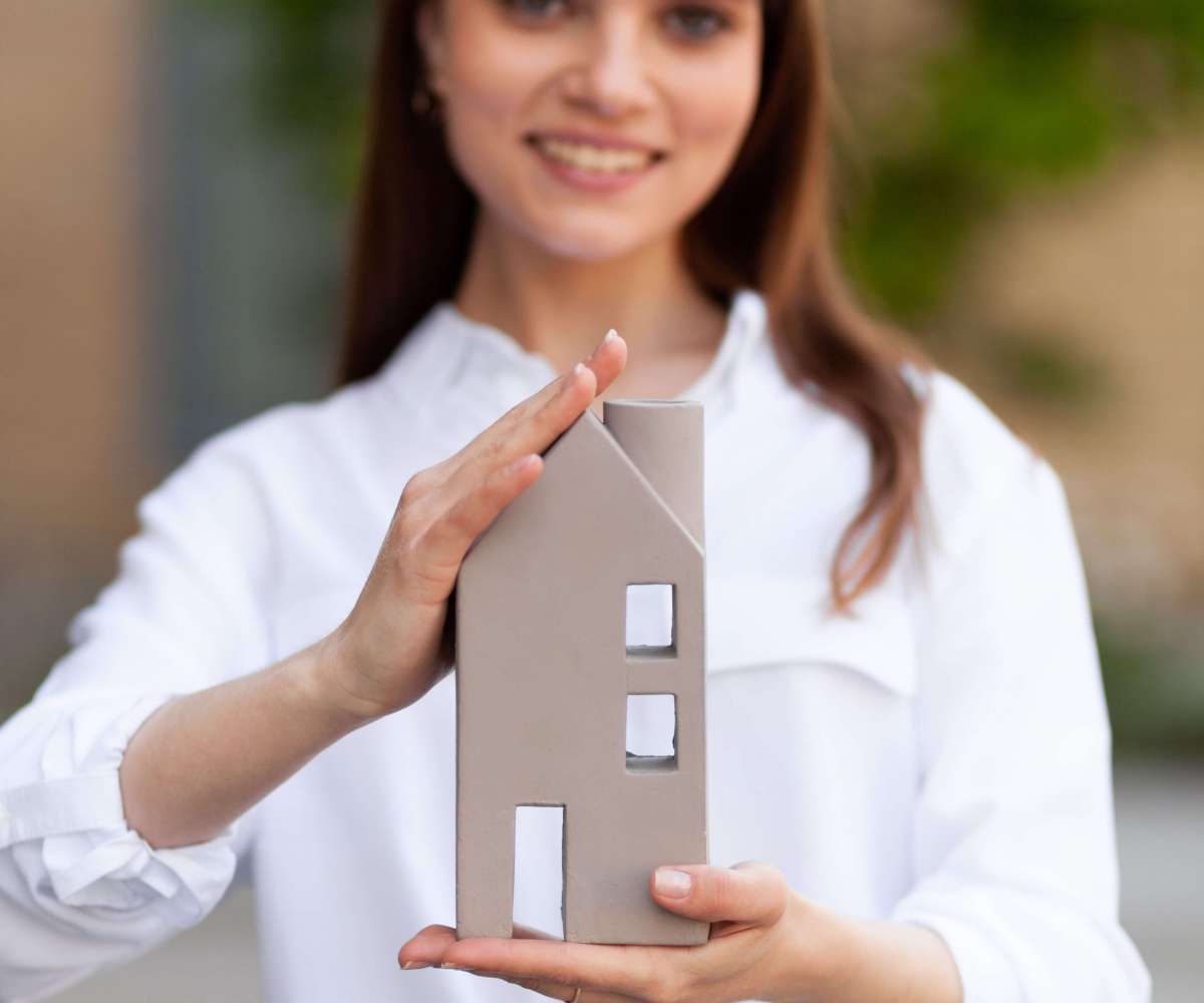 commision immobilier - une agent immobilier tenant une maquette de maison entre ses mains