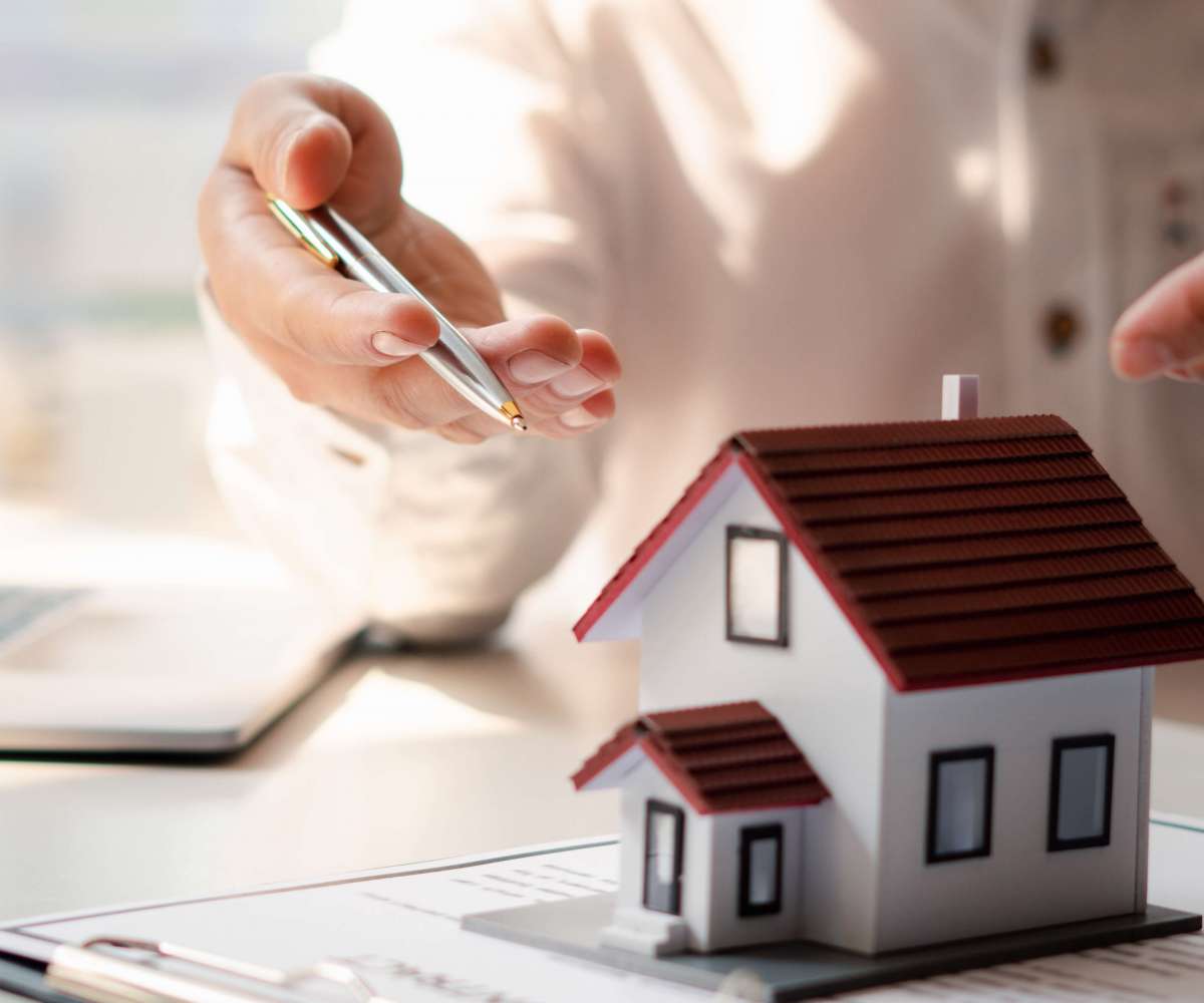 Profession agent immobilier - un agent présentant un projet avec une maison miniature sur des documents
