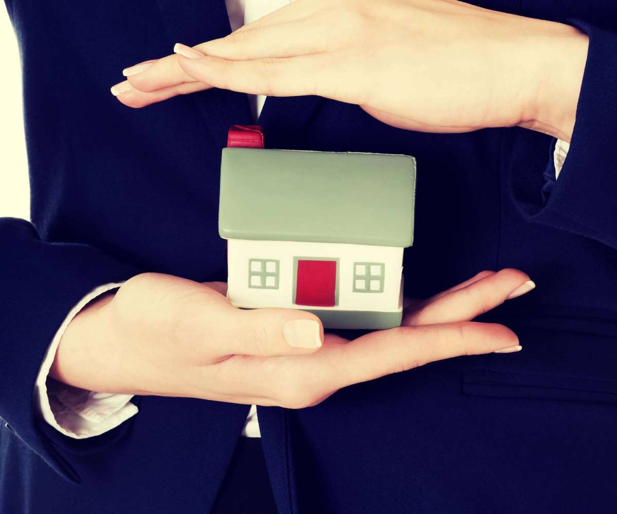 statut agent immobilier - un mandataire immobilier tenant entre ses mains une maison miniature