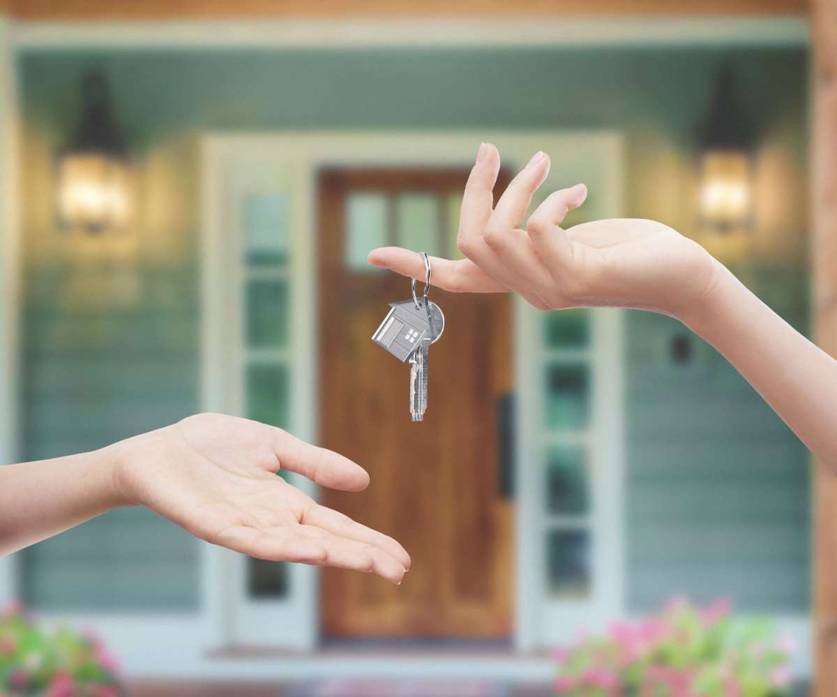 frais d’agence à la charge du vendeur - Une main donnant des clés à une autre devant la porte d'une maison