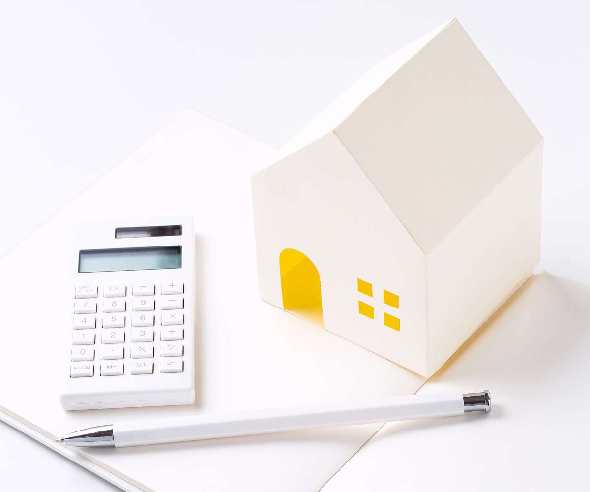 hai immobilier - Un miniature de maison, un stylo et une calculette posés sur un carnet