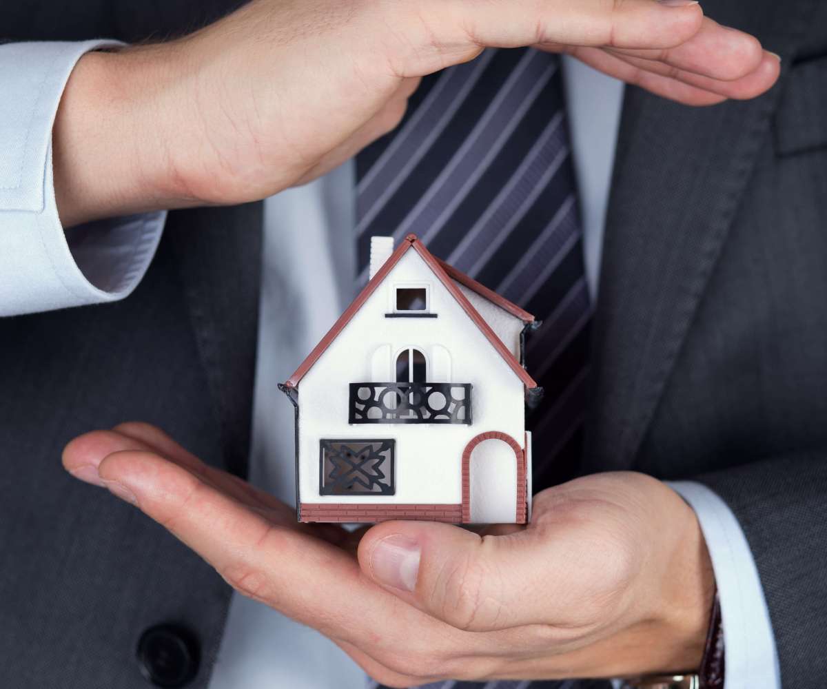 devenir agent commercial immobilier - un agent immobilier tenant entre ses mains une maison miniature