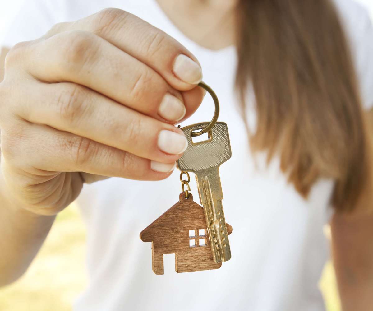comment rédiger une offre d’achat - Une femme tendant entre ses doigts les clés d'une maison